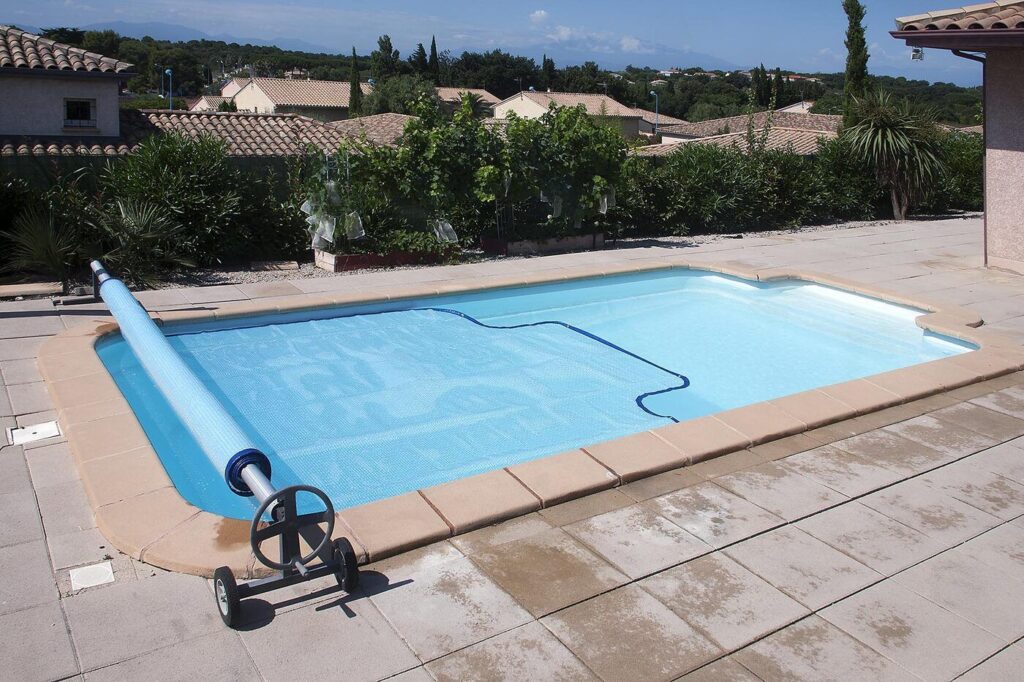 Bâche à bulles bleue posée sur une piscine, avec son enrouleur
