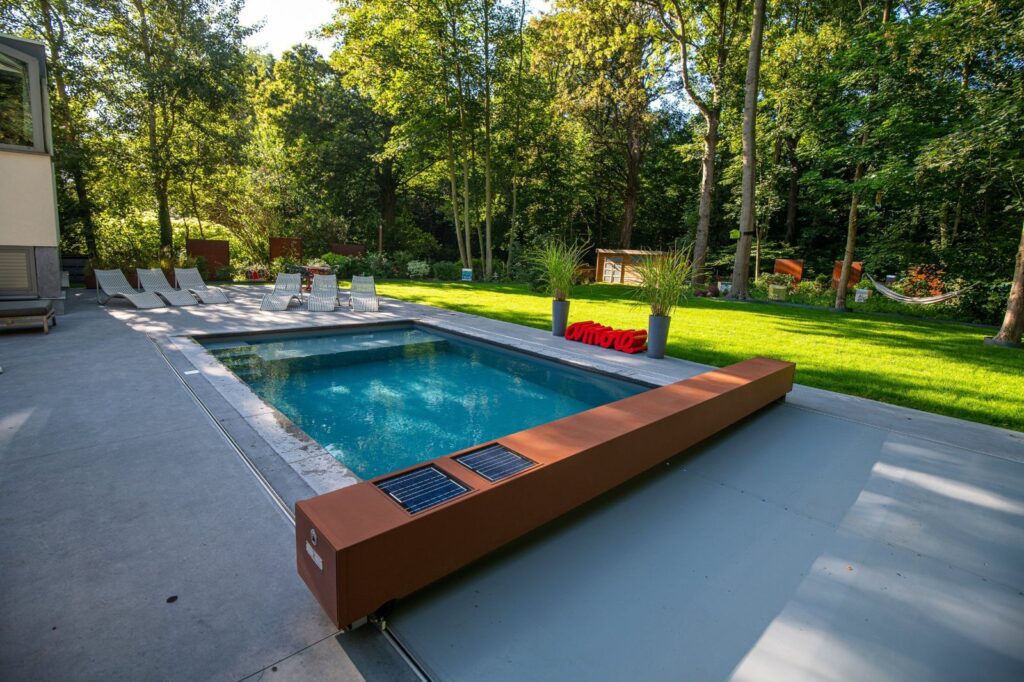 Caisson Coverseal couleur rouille avec deux panneaux solaires, piscine ouverte derrière