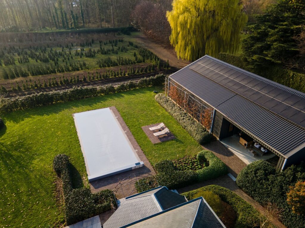 Vue aérienne d’une piscine fermée par une couverture Coverseal grise dans un grand jardin