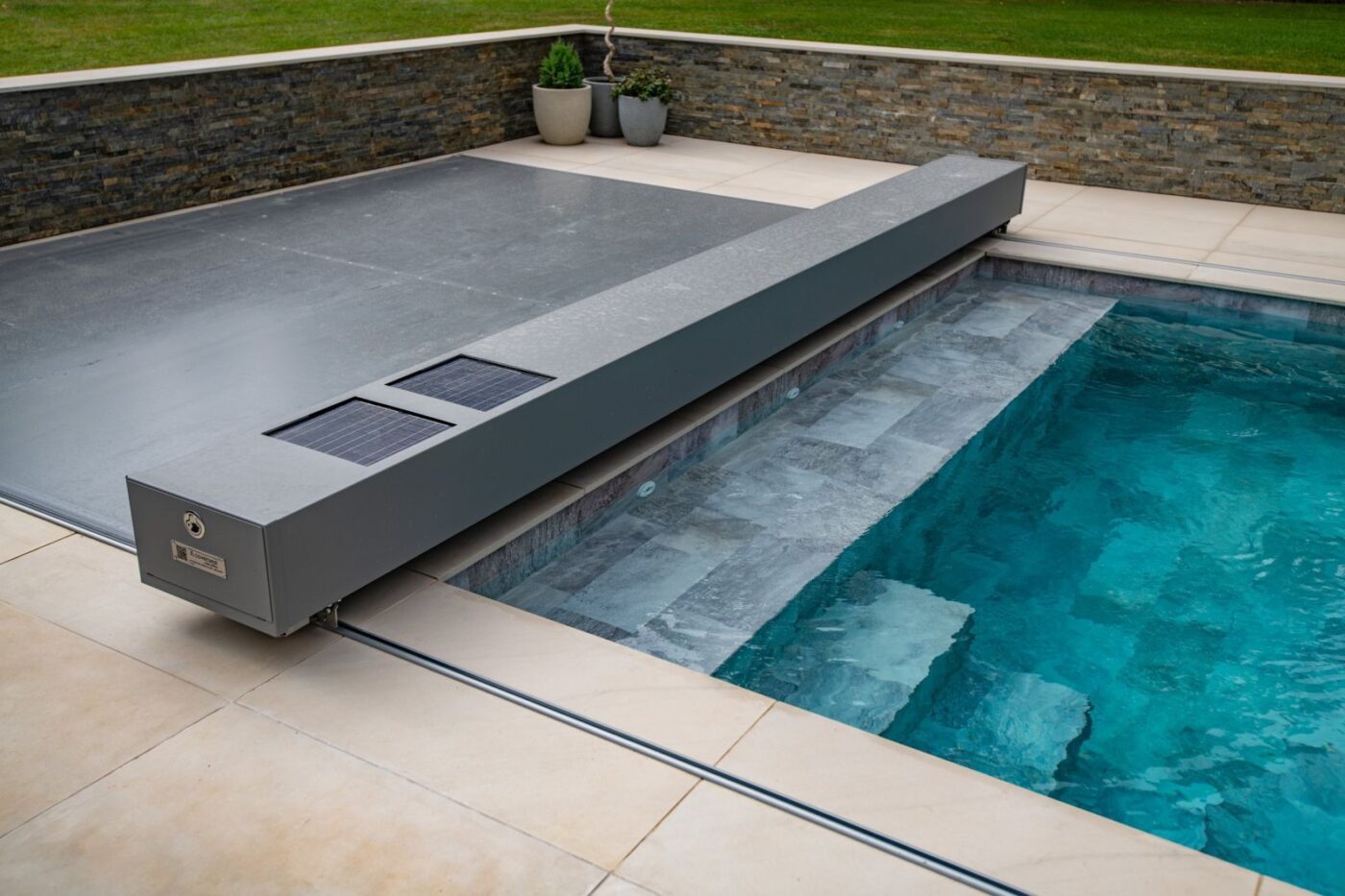 Couverture de piscine à caisson solaire au bord d’une piscine carrelée